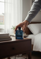 CRYOGEAR hand decanted Bleu de Chanel Eau de Parfum bottle on a wooden nightstand with a man's hand reaching for it.